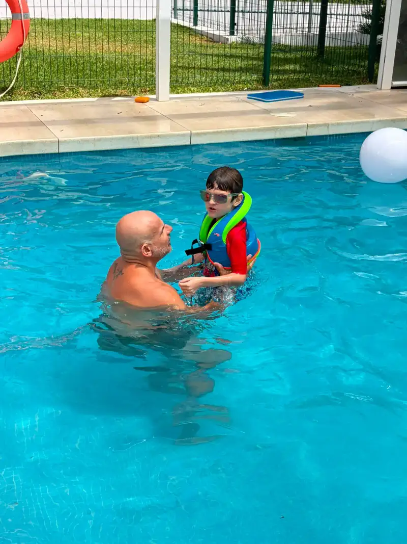 Instructor acompañando a un niño durante una clase de natación infantil en la piscina de Casa Ángeles en Marbella.